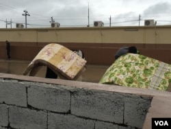 Men carrying foam mattresses in a refugee camp set up for villagers fleeing IS control outside Makhmour, Iraq, April 11, 2016. (S. Behn/VOA)