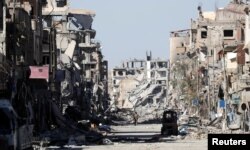 A fighter of Syrian Democratic Forces stands amid the ruins of buildings near the Clock Square in Raqqa, Syria, Oct. 18, 2017.