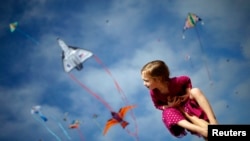 Madeleine Klonoski, 2, sits on her father's leg at a kite festival in Redondo Beach, California, March 8, 2015. 