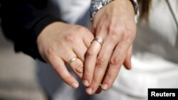 A same-sex couple displays rings in honor of their civil union, legal for the first time in Santiago, Chile, Oct. 22, 2015.