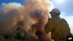 FILE: A firefighter watches as smoke rises from a wildfire in Goleta, California, Oct. 13, 2021.