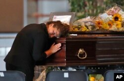 A woman mourns a victim of a collapsed highway bridge, at the Fiera di Genova exhibition center, where some of the coffins are laid in state, in Genoa, Italy. A state funeral for most of the victims will take place in Genoa on Saturday.