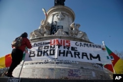 A Cameroonian man living in exile in France adjusts a banner that reads,"Cameroon united against Boko Haram," at the Republique plaza in Paris, Feb. 7, 2015.