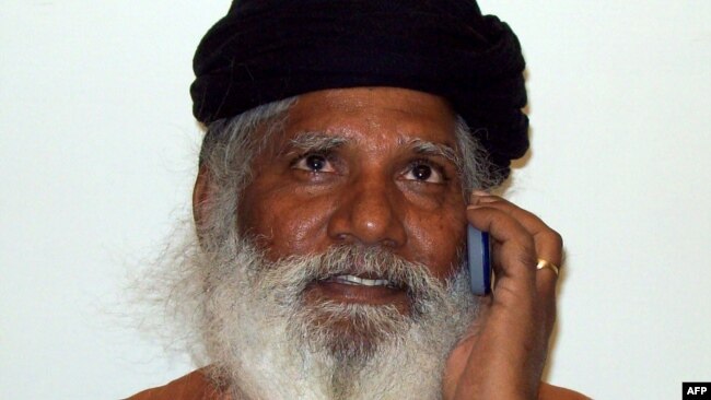 FILE - Hindu priest Bharatdas Darshandas talks on his mobile phone at a private news channel studio in Rajkot, India, March 2, 2009