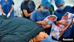 FILE - Nurses show a pair of fraternal twins to their mother (bottom) after they were born at the IVF centre of a hospital in Xi'an, Shaanxi province.