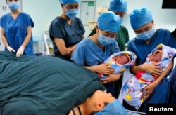 FILE - Nurses show a set of fraternal twins to their mother, bottom, after they were born in a hospital in Xi'an, Shaanxi province.