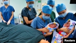 FILE - Nurses show a pair of fraternal twins to their mother (bottom) after they were born at the IVF centre of a hospital in Xi'an, Shaanxi province.