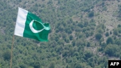 FILE - A Pakistani flag flies at Manatu mountain in the central part of Kurram Agency, Pakistan's tribal belt bordering Afghanistan, July 10, 2011. 
