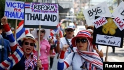 Anti-government protesters carry signs against ousted Prime Minister Yingluck Shinawatra as they march in central Bangkok, May 8, 2014. 
