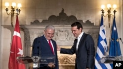 FILE - Greek Prime Minister Alexis Tsipras, right, shows the way to his Turkish counterpart Binali Yildirim, at the end of their joint news conference in Athens, Monday June 19, 2017.