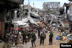Government soldiers stand in front of damaged houses and buildings in Marawi city, Philippines, Oct. 25, 2017.