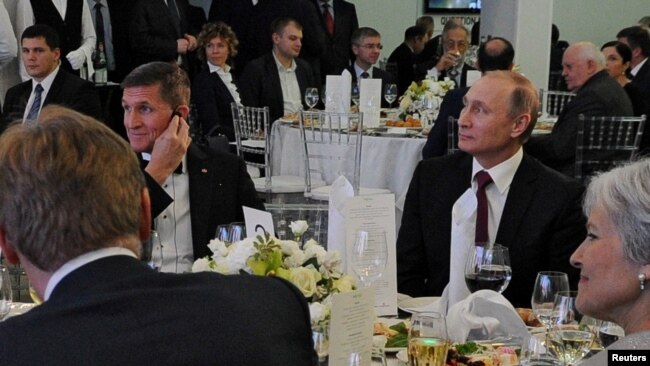 FILE - Russian President Vladimir Putin (R) sits next to retired U.S. Army Lieutenant General Michael Flynn (L) as they attend an exhibition marking the 10th anniversary of RT (Russia Today) television news channel in Moscow, Russia, Dec.10, 2015.