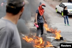 A demonstrator lights up a barricade during a protest against the re-election of Honduran President Juan Orlando Hernandez in Tegucigalpa, Honduras, Jan. 20, 2018.