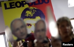 FILE - People hold portraits of opposition leader Antonio Ledezma in front of a wall with a portrait of opposition leader Leopoldo Lopez during a news conference at the Venezuelan coalition of opposition parties headquarters in Caracas, Venezuela, Aug. 1, 2017.