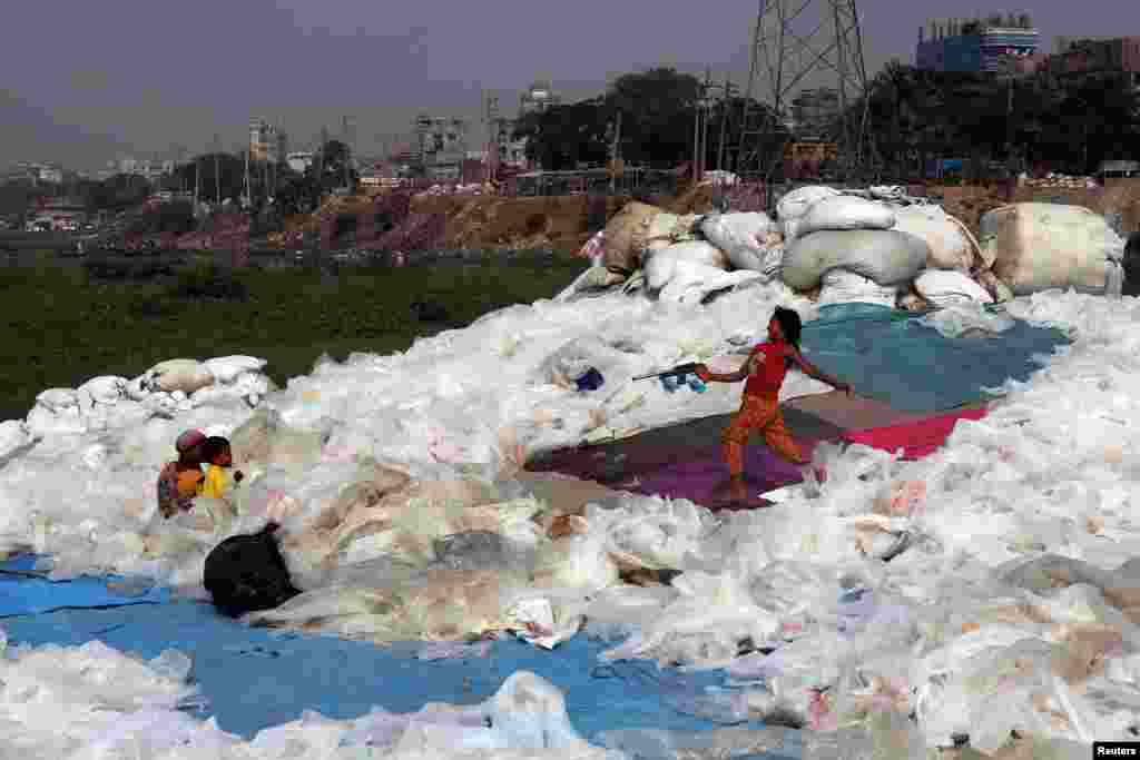 A girl plays with a toy gun at a plastics recycling area in Dhaka, Bangladesh.