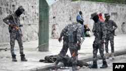 Des soldats somaliens regardent le corps d'un prétendu combattant Al Shabab abattu sur le lieu d'un attentat suicide à la voiture piégée à Mogadiscio le 6 avril 2018.