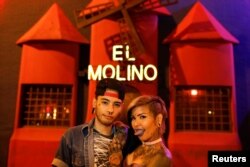 Tattoo artists, Kathriel Zambrano (L), 23, and Yohanna Gonzalez, 28, pose for a portrait in front of the bar El Molino where they first met, in Caracas, Venezuela, Feb. 9, 2018.