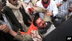 A wounded Yemeni anti-government protester is carried away by fellow demonstrators in Sana'a March 18, 2011
