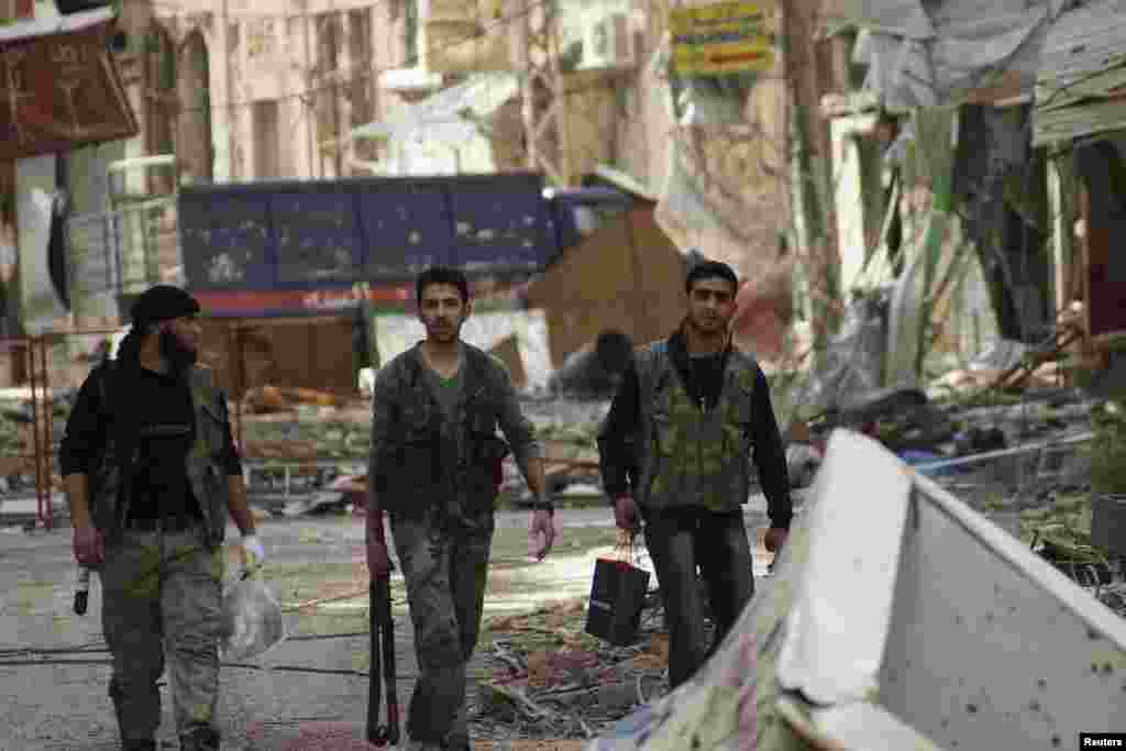 Free Syrian Army fighters walk along a street lined with damaged shops and buildings in Deir al-Zor, April 8, 2013.