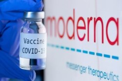 Ampul bertuliskan vaksin Covid-19 di depan logo Moderna, 18 November 2020.