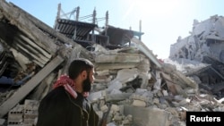 2月12日一名叙利亚自由军战士手持武器走过大马士革被摧毁的社区