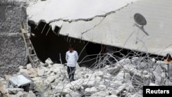 A resident walks upon the debris of buildings which were damaged in what activists say was one of Tuesday's U.S. air strikes in Kfredrian, Idlib province September 24, 2014.