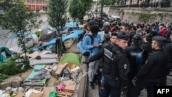 Des policiers français anti-émeutes pendant l'évacuation d'un camp de migrants et de réfugiés le long du canal de Saint-Martin, Quai de Valmy, à Paris le 4 juin 2018.