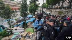Les policiers anti-émeutes évacuent un camp de réfugiés le long du canal de Saint-Martin au Quai de Valmy à Paris.