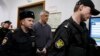 Founder of the Baring Vostok investment fund Michael Calvey, center, is escorted to the courtroom in Moscow, Feb. 15, 2019. A veteran U.S. investment fund manager has been detained in Moscow and faces fraud charges.