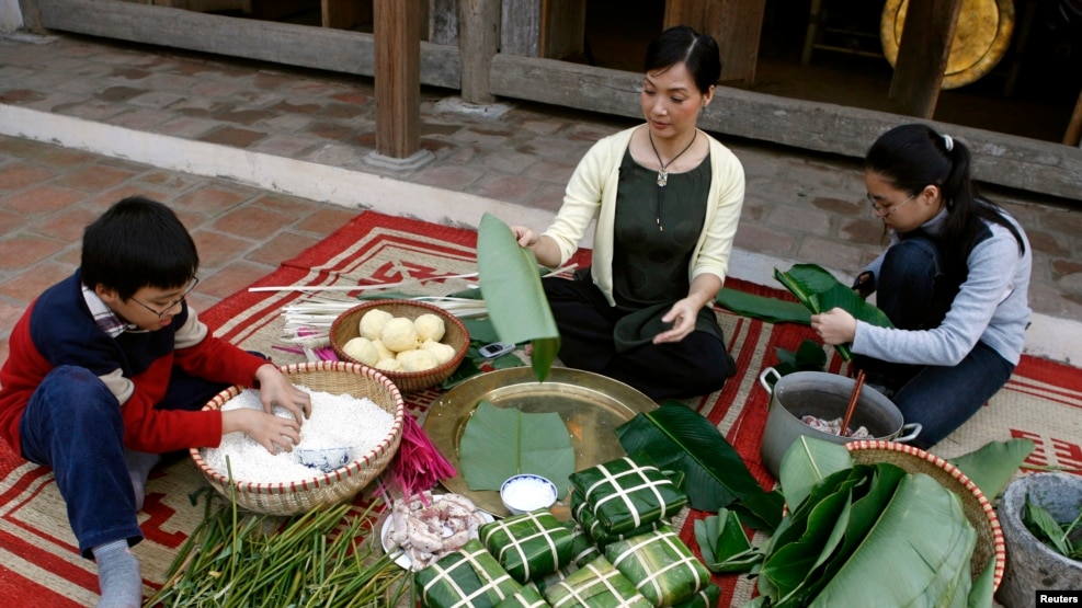 Gia đình nghệ sĩ Lê Khanh gói bánh chưng. Bánh chưng làm theo triết lý âm dương có hình vuông tượng trưng mặt đất, trên đó có nếp, đậu, thịt.