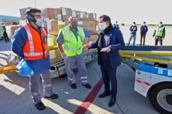 Handout picture released by the Buenos Aires province Ministry of Public Communication showing Buenos Aires province Governor Axel Kicillof (R) speaking with workers while the unloading of boxes containing medical supplies coming from China.