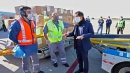 Handout picture released by the Buenos Aires province Ministry of Public Communication showing Buenos Aires province Governor Axel Kicillof (R) speaking with workers while the unloading of boxes containing medical supplies coming from China.