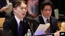 Koichiro Iizuka, left, of Japan, speaks during a meeting as Takuya Yokota, right, listens, May 3, 2018, at the United Nations headquarters. 