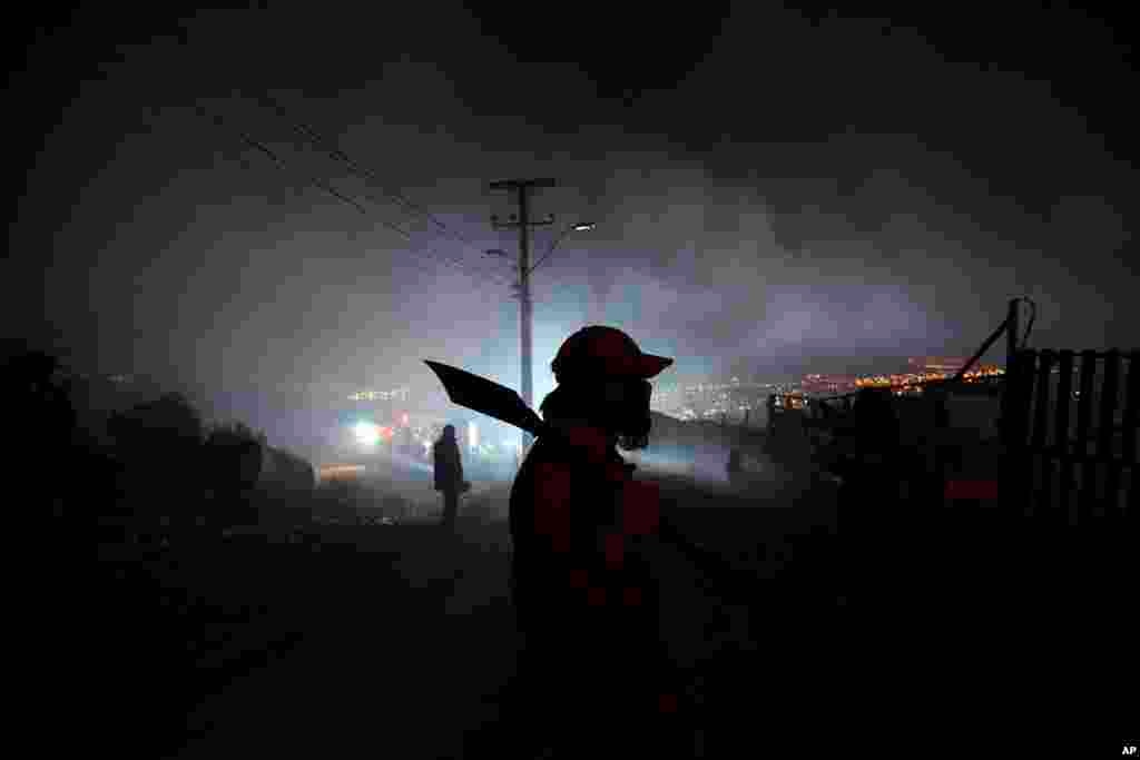 A resident helps to extinguish flames as an out of control forest fire destroys homes in the city of Valparaiso, Chile, April 13, 2014.