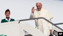 Pope Francis waves to reporters at Rome's Fiumicino international airport, July 5, 2015, as he boards his flight to Quito, Ecuador, where he will start a week-long trip to South America, including Bolivia and Paraguay. 