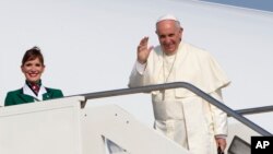 Paus Fransiskus melambaikan tangan ke arah wartawan di bandara internasional Roma, Minggu (5/7) sebelum memasuki pesawat menuju Quito, Ekuador. (AP/Riccardo De Luca)