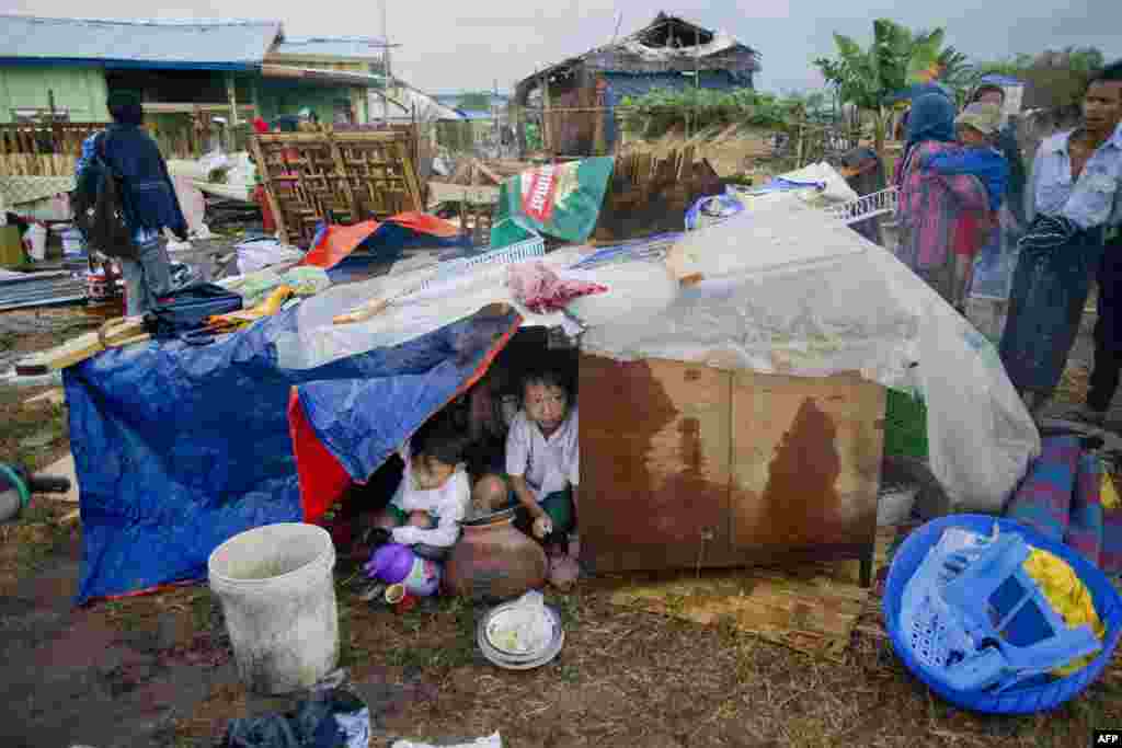 Burma&#39;da, hükümetin yıktığı gecekondularının yıkıntıları arasında oturan çocuklar.