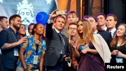 French president Emmanuel Macron takes a selfie with participants of the Charlemagne Youth Prize on the podium of a European Feast in Aachen, Germany, May 9, 2018.