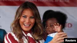 លោកជំទាវ Melania Trump ពរទារកមួយ អំឡុងពេលដំណើរទស្សនកិច្ចទៅកាន់​មន្ទីរពេទ្យ​មួយ នៅ​ប្រទេស​ហ្គាណា កាលពីថ្ងៃទី០២ ខែតុលា ឆ្នាំ២០១៨។ 