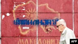 A man passes in front of graffiti with an old map of Macedonia referring to the long-running name dispute with neighboring Greece, in Skopje, June 13, 2018. (AFP PHOTO / Robert ATANASOVSKI)