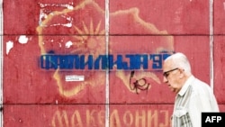A man passes in front of graffiti with an old map of Macedonia referring to the long-running name row with neighboring Greece, in Skopje, June 13, 2018.