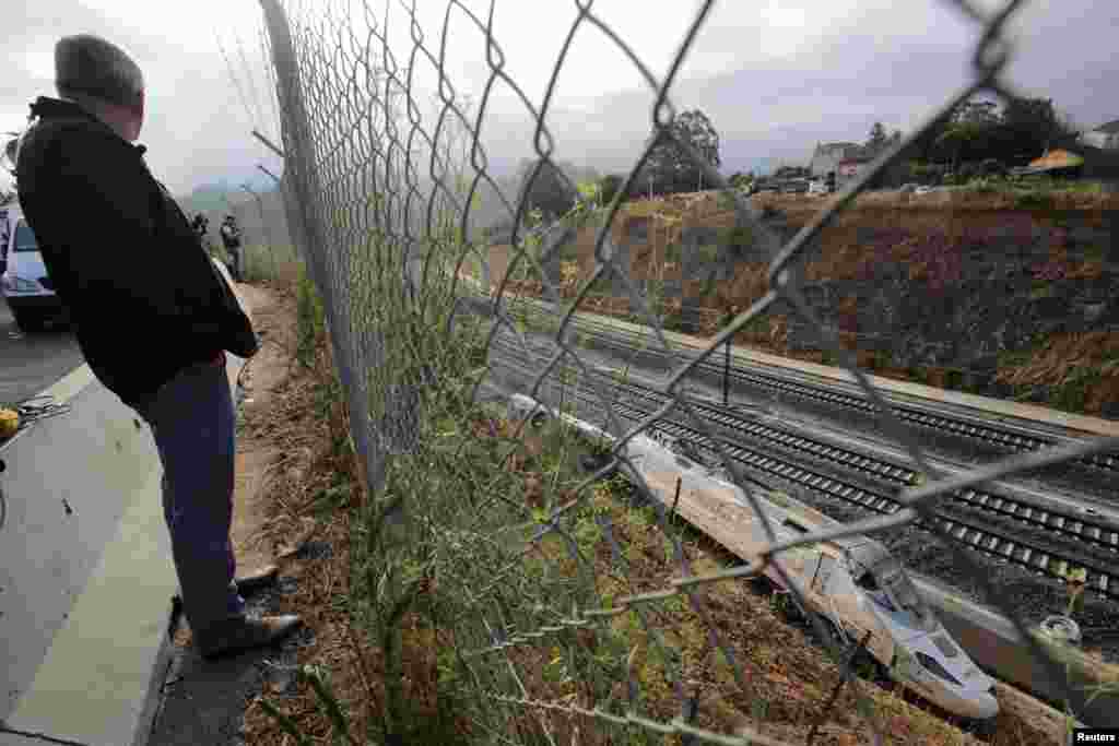 Seorang laki-laki melihat lokomotif kereta api di lokasi kecelakaan kereta api yang menewaskan paling sedikit 80 orang hari Rabu di Santiago de Compostela, Spanyol barat laut.
