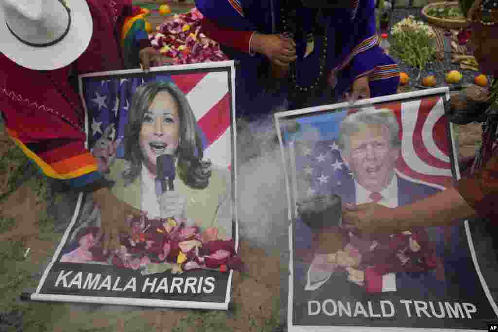 Shamans perform a good luck ritual holding posters of Democratic presidential nominee Vice President Kamala Harris and Republican presidential nominee former President Donald Trump, at the beach in Lima, Peru.