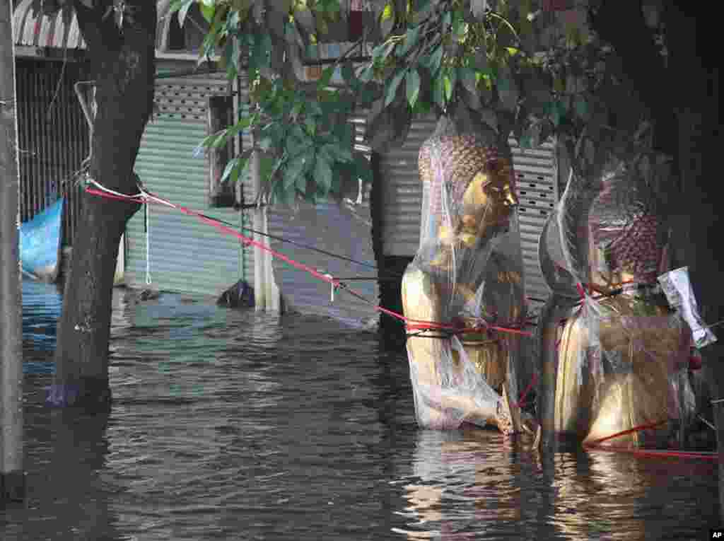 Buddha images are wrapped in plastic and tethered to trees so they don't float away in the waist-deep water in Phet Kasem, Bangkok, November 9, 2011. (VOA - G. Paluch)