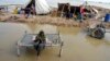 FILE - A woman, surrounded by floodwaters, sits near her belongings, in Sohbat Pur, Pakistan, Sep. 3, 2022. The flooding that year killed at least 1,700 people. The nation's weather officials reported on May 3, 2024, that Pakistan last month had its wettest April since 1961.