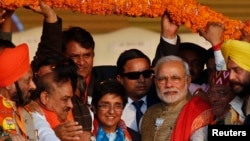 Supporters of India's ruling Bharatiya Janata Party (BJP) present a garland to Prime Minister Narendra Modi, third from right, and BJP's chief ministerial candidate for Delhi Kiran Bedi, center, during a campaign rally ahead of state assembly elections in