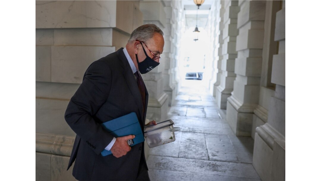 U.S. Senate Majority leader Chuck Schumer, D-NY, carries his empty lunch box back into the Capitol as the Senate continues to work through the bipartisan infrastructure bill, in Washington, August 9, 2021.