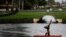 A man stands on his head on a paddle board as pollice officers look at him during a protest against racial inequality in the aftermath of the death in Minneapolis police custody of George Floyd, outside Trump National Doral golf resort in Doral, Florida, 