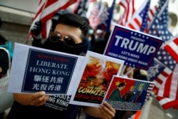 A masked protester holds placards during a "March of Gratitude to the US" event in Hong Kong, Dec. 1, 2019.