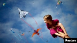Madeleine Klonoski, 2, sits on her father's leg at a kite festival in Redondo Beach, California, March 8, 2015. 